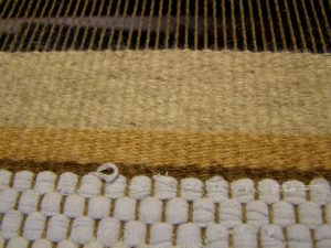 Close up of hand weaving on loom